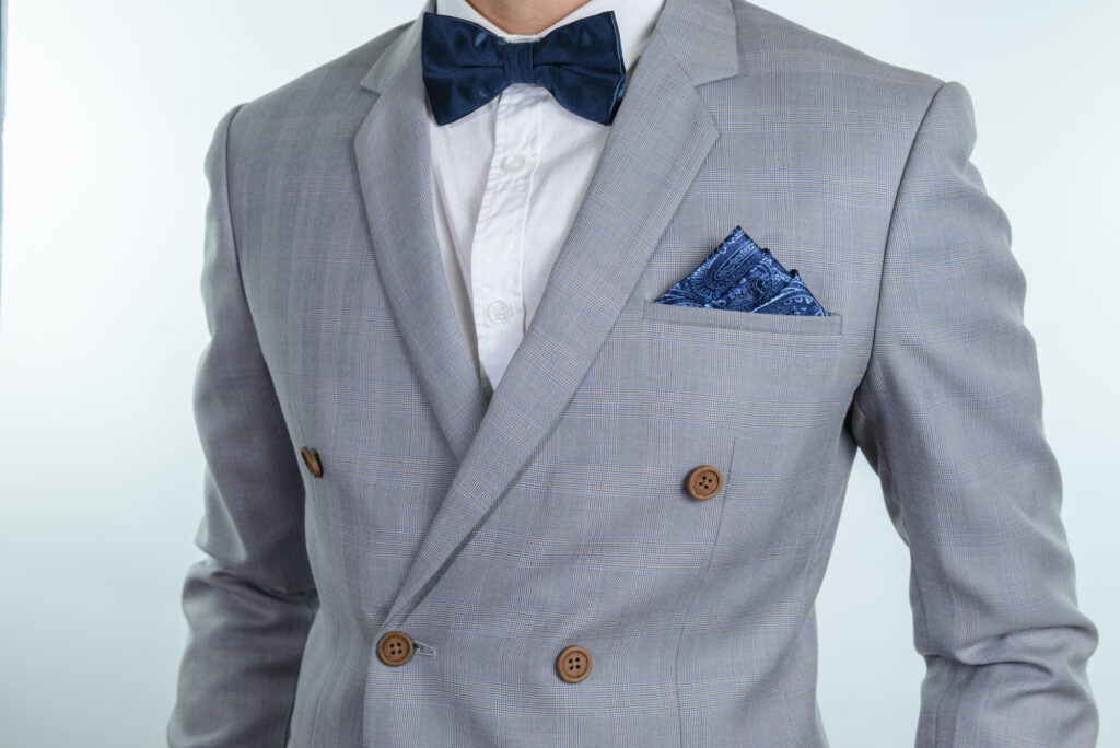 グレーのスーツにブルーの蝶ネクタイとポケットチーフを合わせた着こなしをした男性