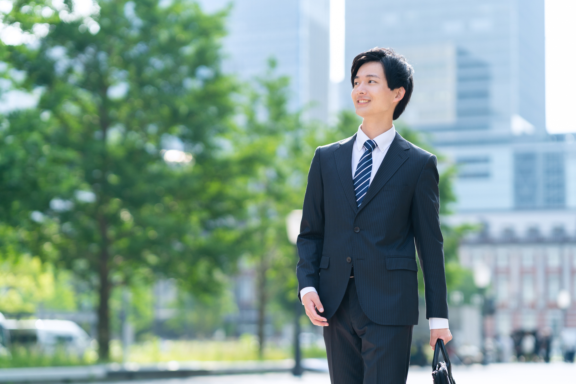 公園を歩くスーツを着た男性